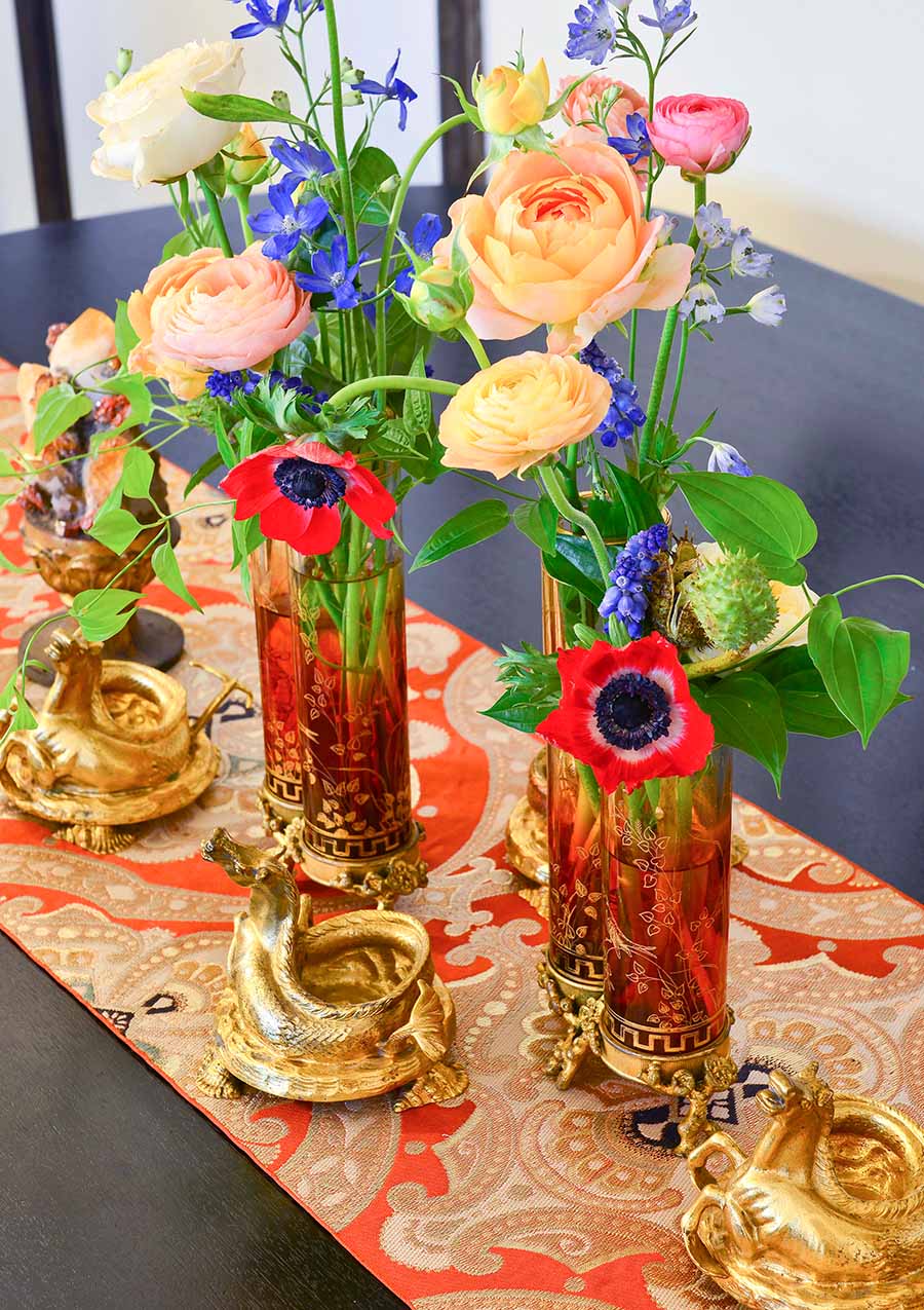 Closeup of dining table with flowers, gilded decor, red runner, dark wood