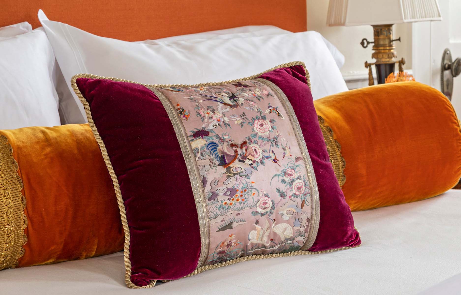 Bedroom pillow closeup with red and orange embroidered pillows