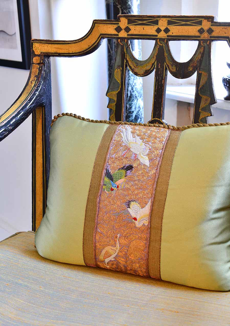 Closeup of gold embroidered pillow on gilded chair